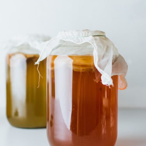 two mason jars filled with liquid on white surface